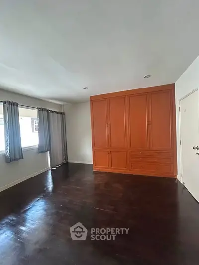 Spacious bedroom with dark wood flooring and built-in wardrobe, perfect for modern living.