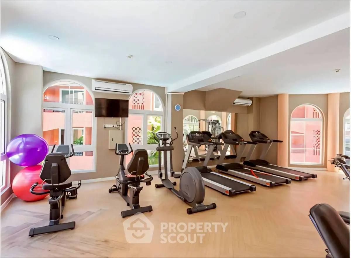 Spacious gym with modern equipment and large windows in a luxury residential building.