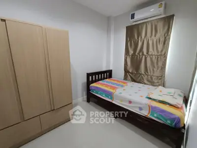 Cozy bedroom with single bed and wooden wardrobe, ideal for minimalist living.