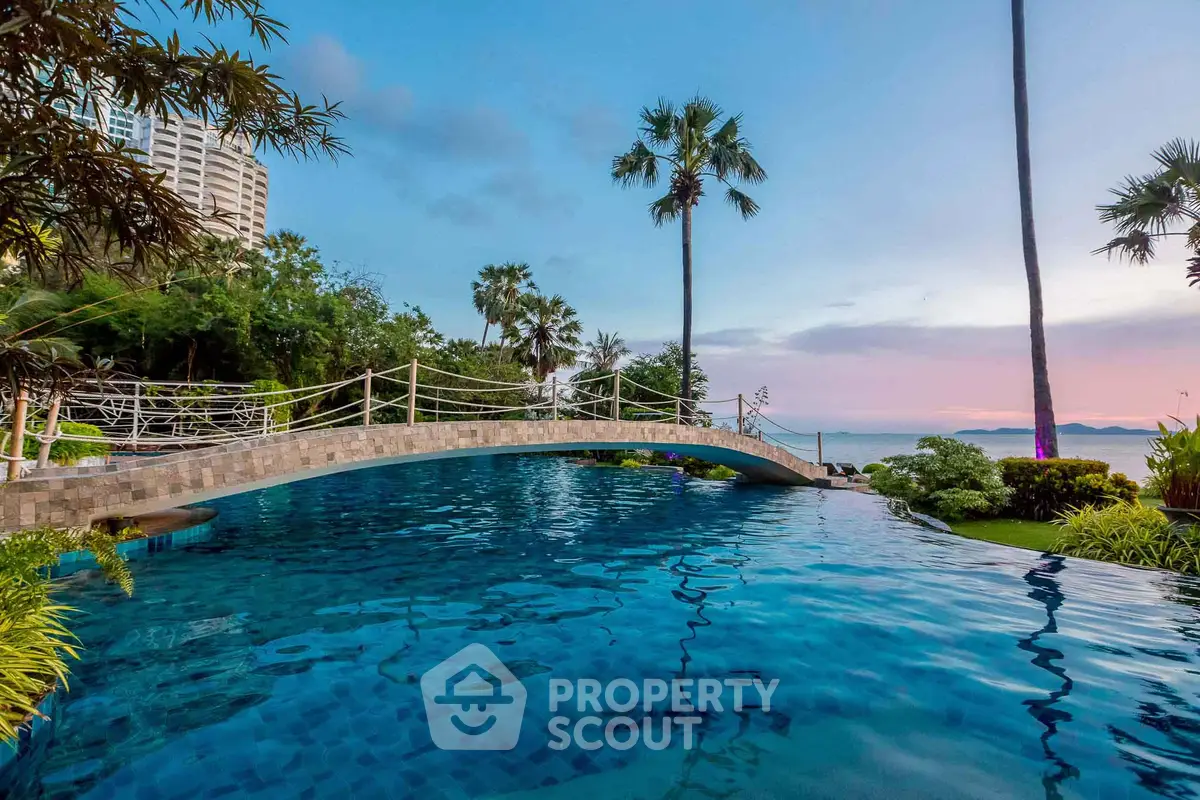 Luxurious poolside view with bridge and ocean backdrop at sunset