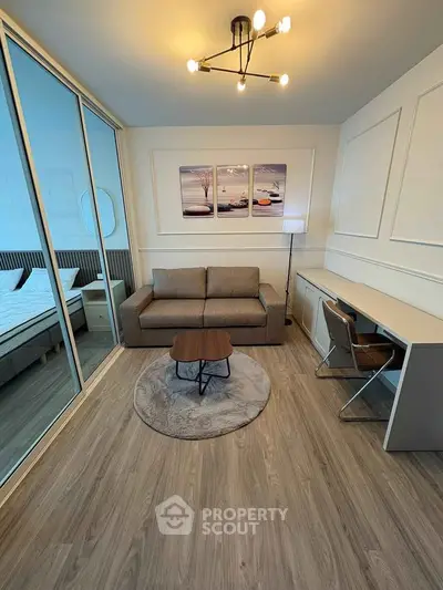 Modern living room with stylish decor and adjacent bedroom, featuring a cozy sofa and sleek desk area.