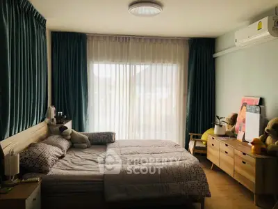 Cozy bedroom with large window, stylish curtains, and modern furnishings for a comfortable living experience.