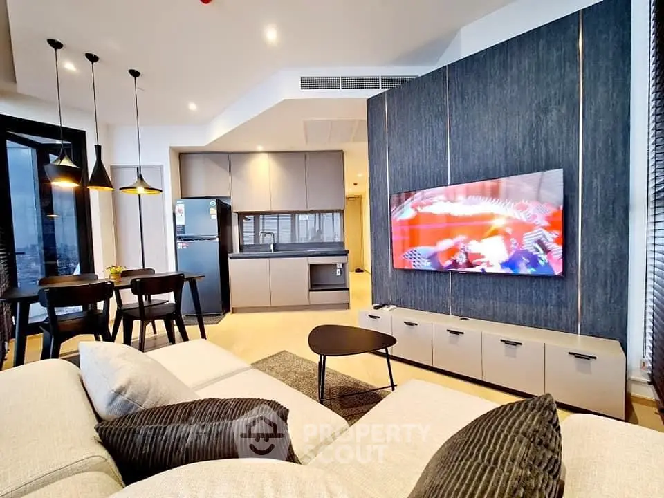 Modern living room with open kitchen, stylish decor, and large TV in a contemporary apartment.