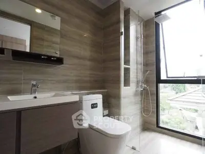 Modern bathroom with sleek design, featuring a glass shower and large window for natural light.