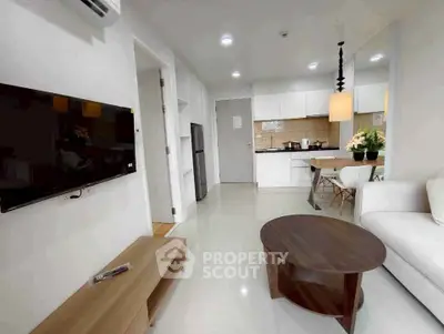 Modern open-layout living room with sleek kitchen, cozy seating, and stylish decor in a contemporary apartment.