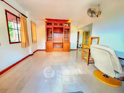 Spacious living room with built-in wooden shelves and large windows for natural light.