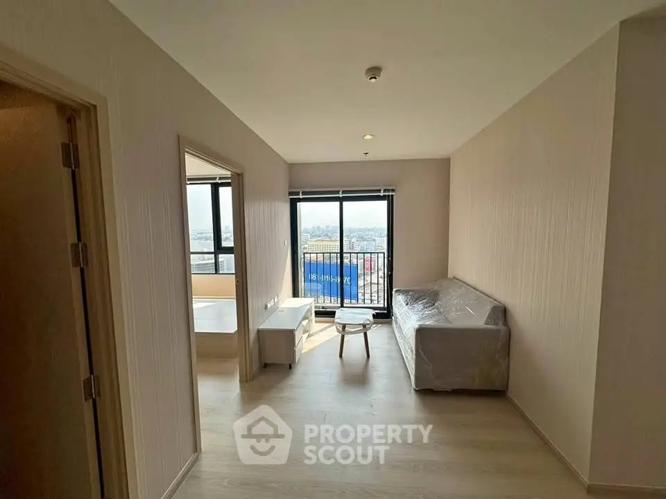 Modern apartment living room with balcony and city view, featuring minimalist furniture and natural light.