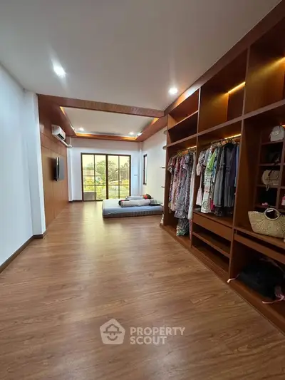 Spacious bedroom with wooden flooring and built-in wardrobe, featuring a large window with a view.