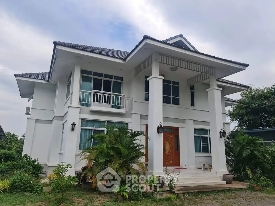 Elegant two-story white house with lush greenery and modern architectural design.