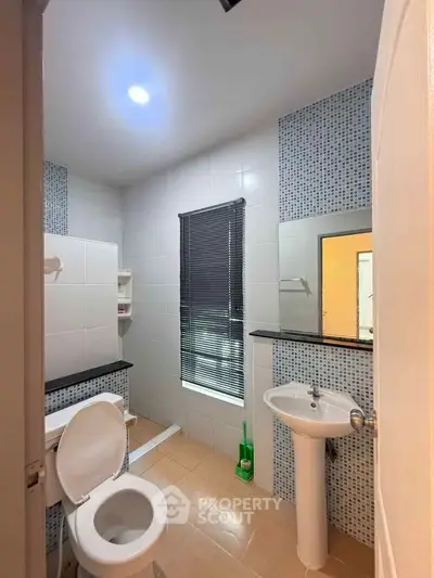 Modern bathroom with sleek fixtures and stylish tile accents, featuring a pedestal sink and toilet.