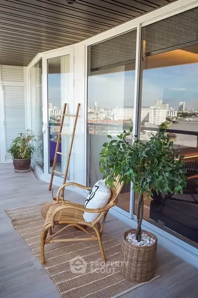 Stylish balcony with city view, featuring rattan furniture and lush greenery for a serene urban retreat.