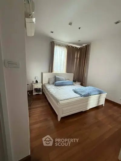 Cozy bedroom with wooden flooring and elegant decor in modern apartment