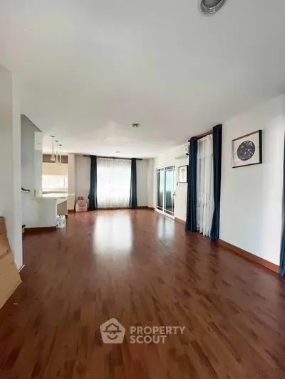 Spacious living room with wooden flooring and large windows for natural light.
