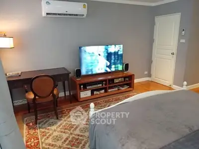 Cozy bedroom with TV and elegant decor, featuring a stylish desk and chair.