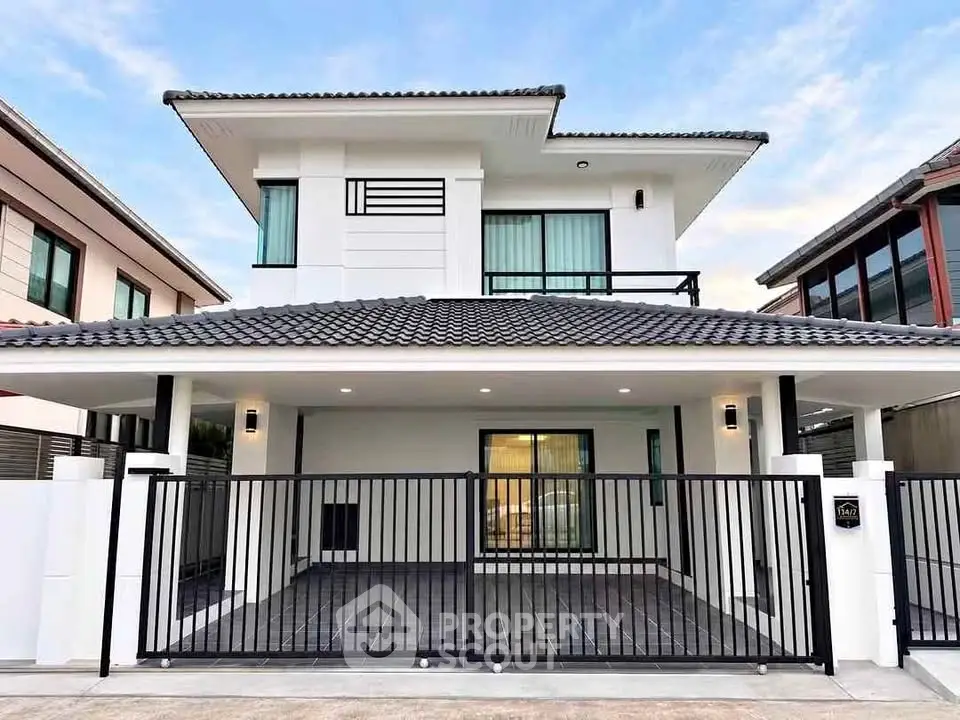 Modern two-story house with sleek design and spacious driveway in suburban neighborhood.