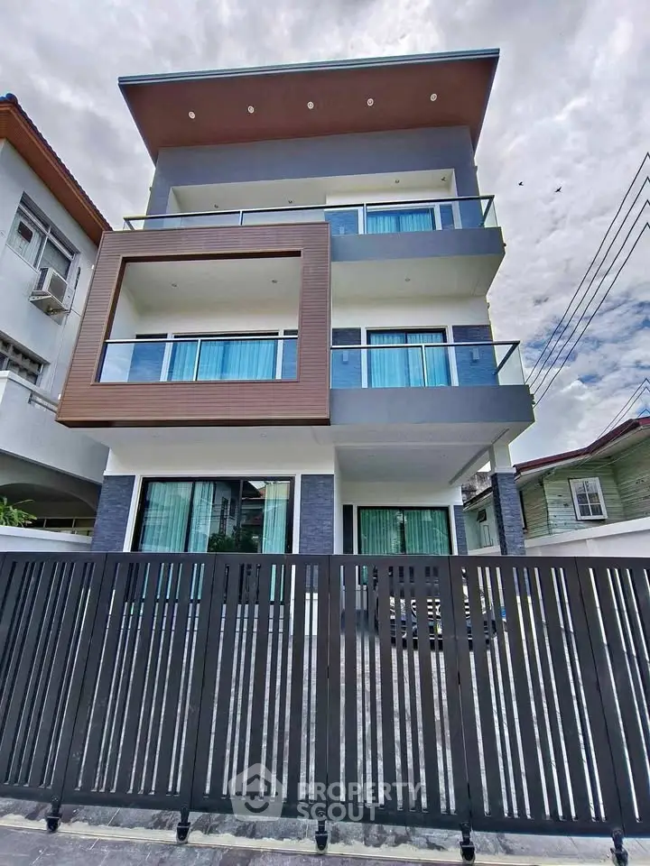 Modern three-story building with sleek design and spacious balconies in urban setting.
