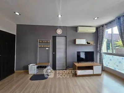 Modern living room with sleek furniture and large window offering natural light.