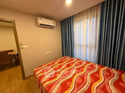 Cozy bedroom with vibrant bedding and air conditioning in modern apartment.