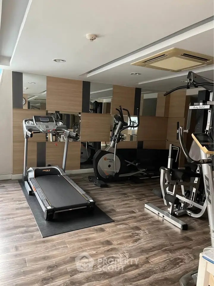 Modern gym with state-of-the-art fitness equipment and stylish wooden flooring.