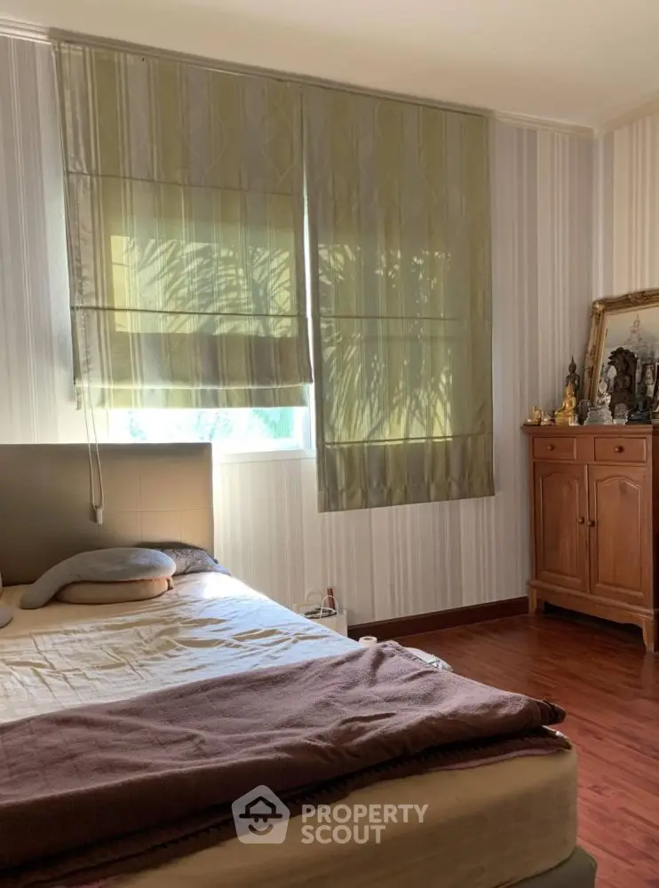 Cozy bedroom with natural light and wooden furniture, perfect for relaxation.