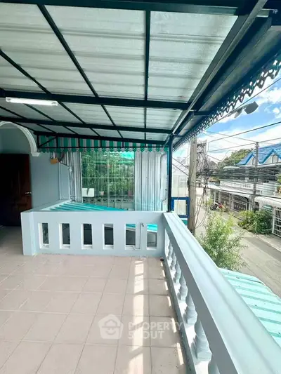 Charming balcony with covered roof and street view, perfect for relaxation.