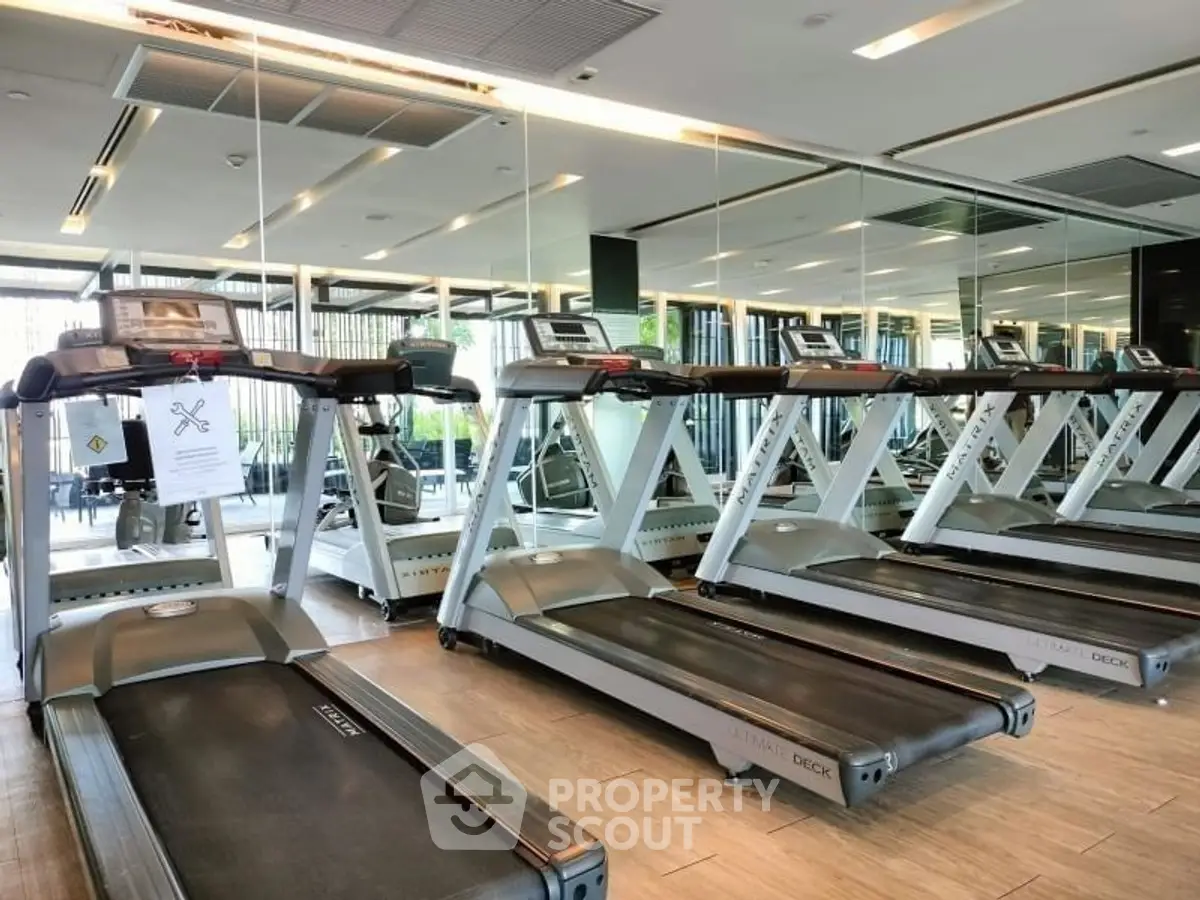 Modern gym with multiple treadmills and mirrored walls in a luxury apartment complex.