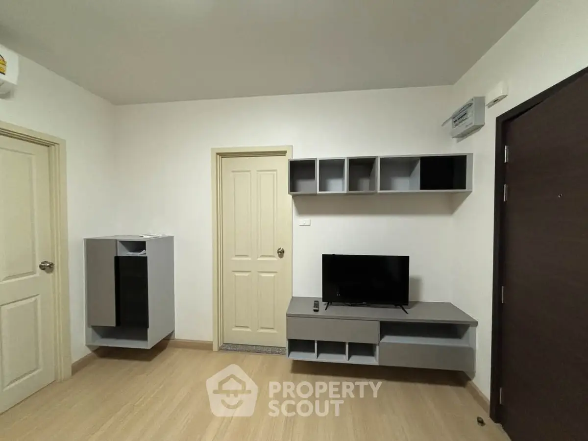 Modern living room with minimalist design, featuring sleek shelving and a compact entertainment unit.