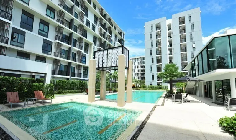 Modern apartment complex with luxurious swimming pool and sun loungers, perfect for relaxation.