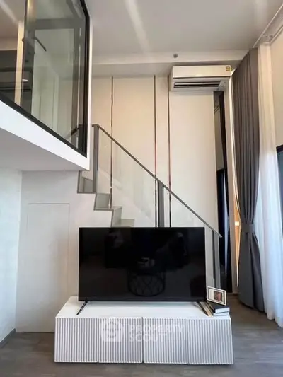 Modern duplex living room with sleek design and large TV under a staircase