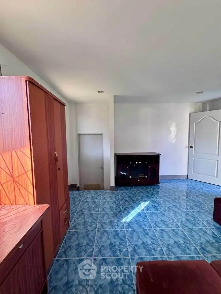 Spacious living room with blue tiled floor and wooden furniture, perfect for cozy gatherings.