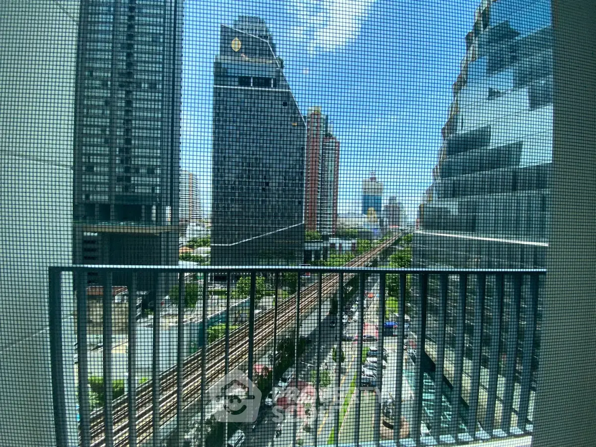 Stunning cityscape view from a high-rise balcony overlooking urban skyline and railway tracks.