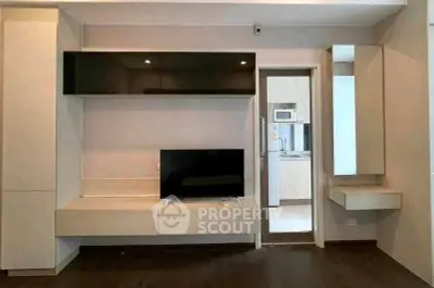 Modern living room with sleek TV unit and view into a contemporary kitchen.
