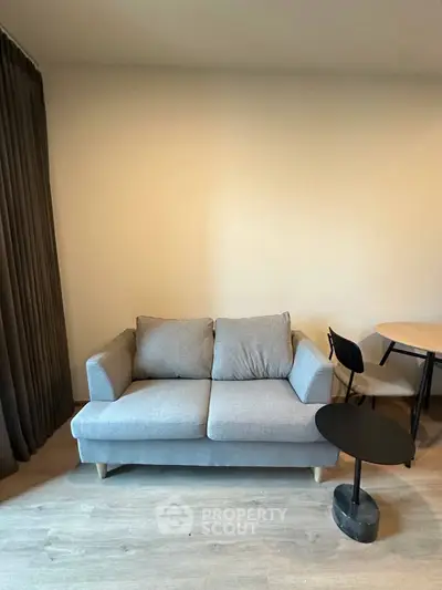 Cozy living room with modern gray sofa and stylish round tables, perfect for relaxation and entertaining.