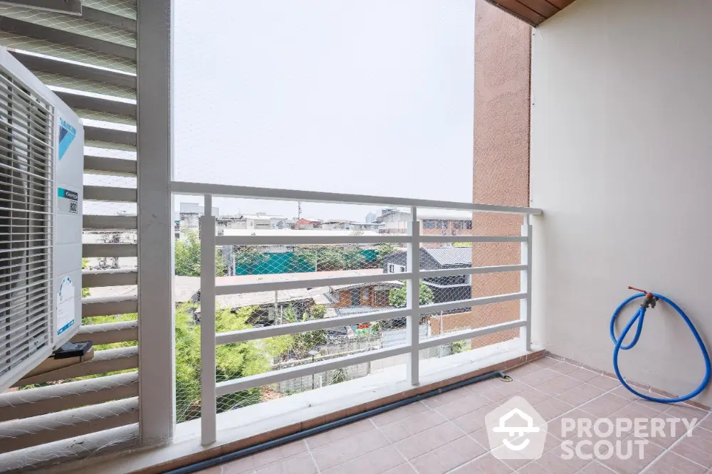 Spacious balcony with city view and air conditioning unit, perfect for relaxation.