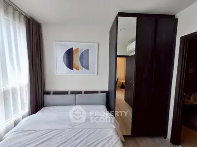 Modern bedroom with stylish decor and ample natural light, featuring a large wardrobe and contemporary artwork.