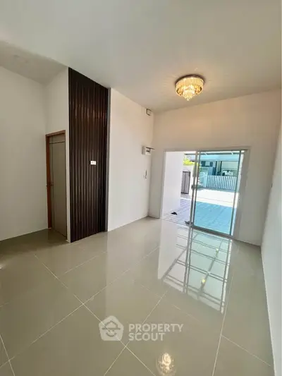 Spacious modern room with elegant chandelier and sliding glass doors leading to a patio.