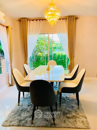 Elegant dining room with chandelier and garden view, featuring modern chairs and a plush rug.