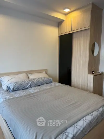 Cozy bedroom with modern wooden wardrobe and stylish bedding in a contemporary apartment.