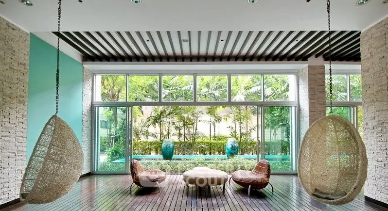 Luxurious modern living room with hanging chairs and garden view, perfect for relaxation.