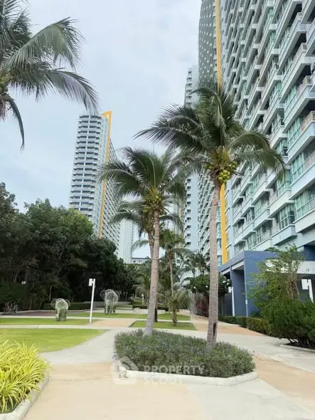Modern high-rise building with lush landscaping and palm trees in a vibrant urban setting.