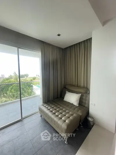 Modern living room with sleek leather sofa and large balcony view.