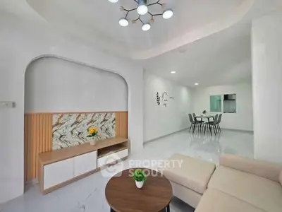 Modern living room with elegant decor and open dining area, featuring stylish lighting and contemporary furniture.
