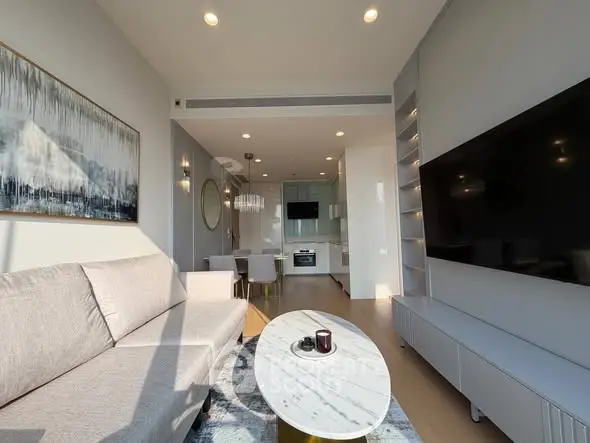 Modern living room with sleek design and open kitchen layout, featuring large TV and stylish decor.