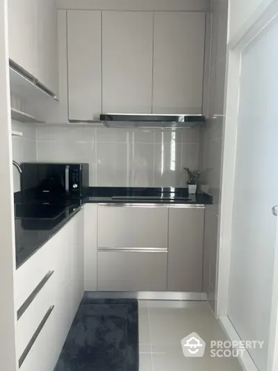 Modern kitchen with sleek cabinetry and black countertops in a compact layout.