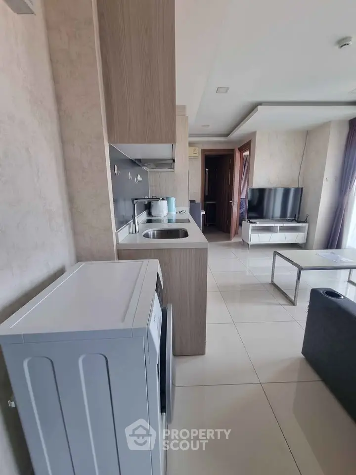 Modern living room with sleek kitchen and washing machine, open layout design.