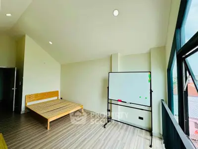 Spacious bedroom with wooden bed frame and large window offering natural light.