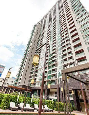 Modern high-rise condominium with outdoor lounge area and lush greenery.