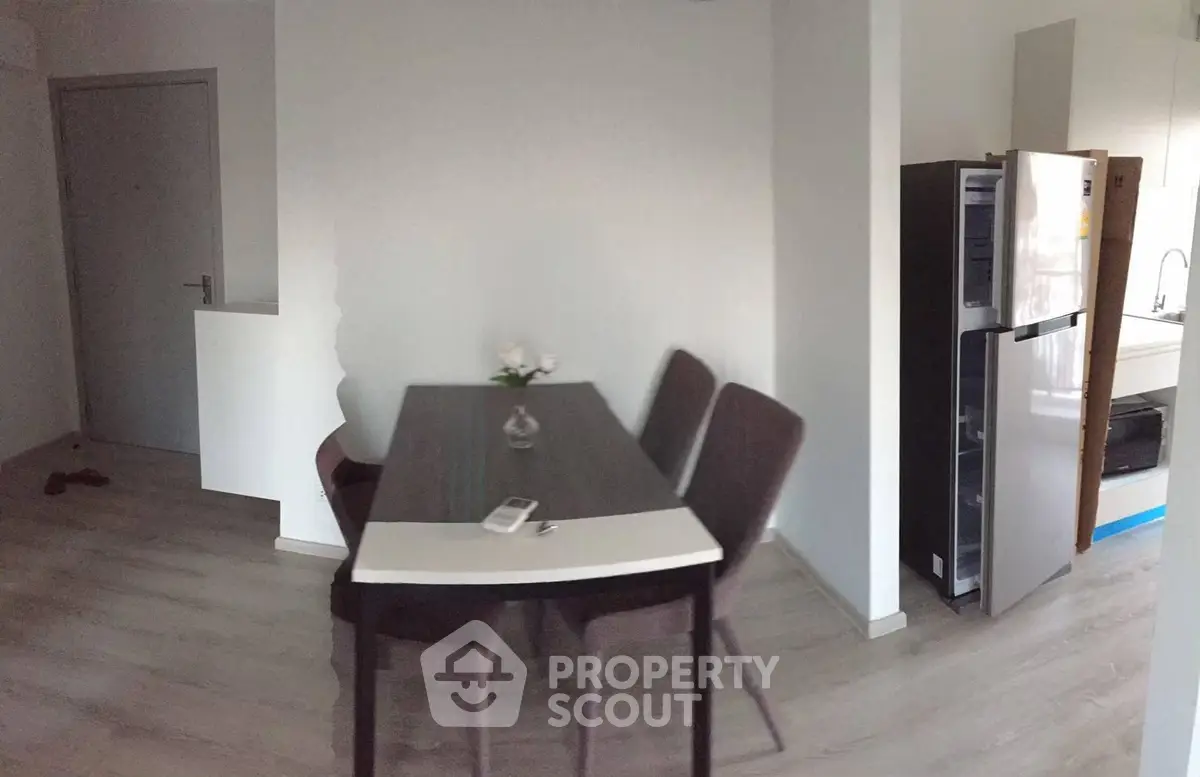 Modern dining area with sleek table and chairs next to a contemporary kitchen.