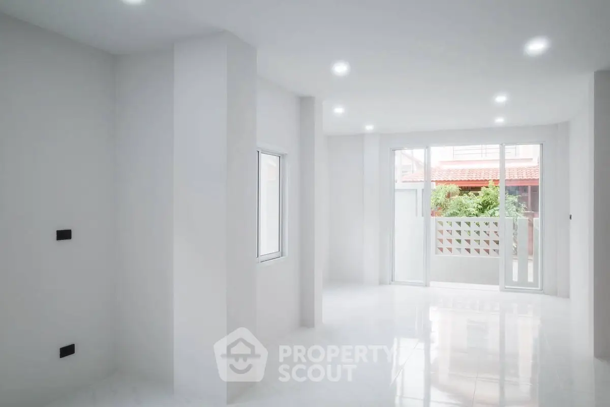 Bright modern living room with large windows and sleek white interior design.