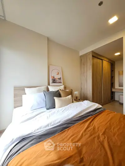 Cozy bedroom with modern decor and ample natural light, featuring a stylish wardrobe and elegant bedding.